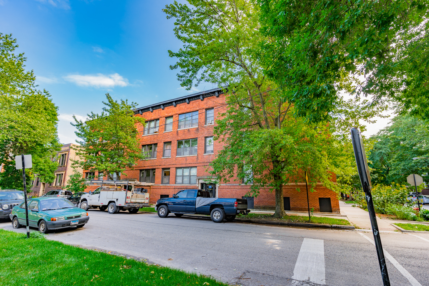 a large red brick building on a street corner with trucks parked in front of it